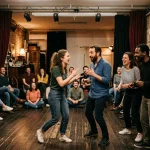 Groupe d’amateurs en atelier théâtre paris 9 : deux personnes au centre improvisent devant un public assis, ambiance chaleureuse et conviviale.