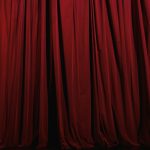 Stage curtains hung across a theater opening, suggesting a performance environment